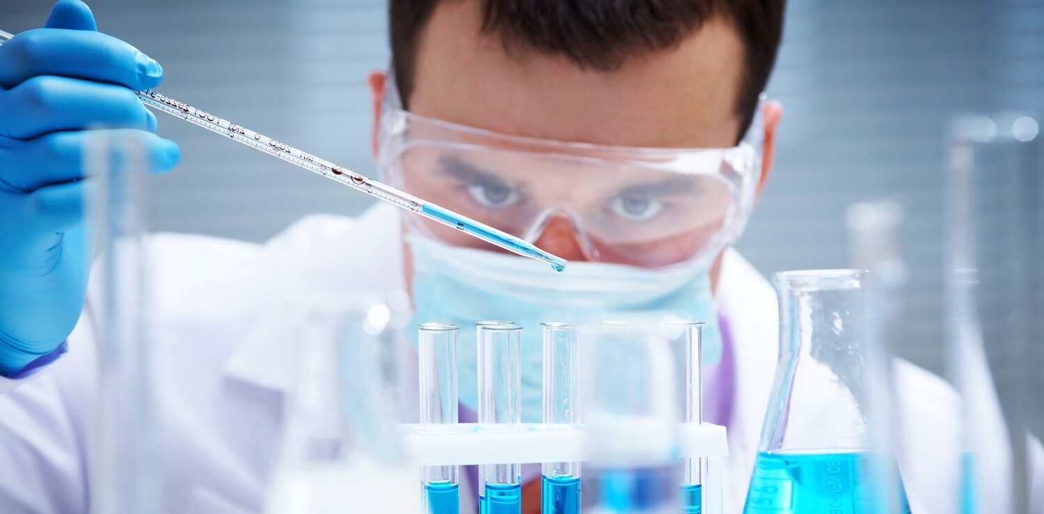 Investigator checking test tubes. Man wears protective goggles